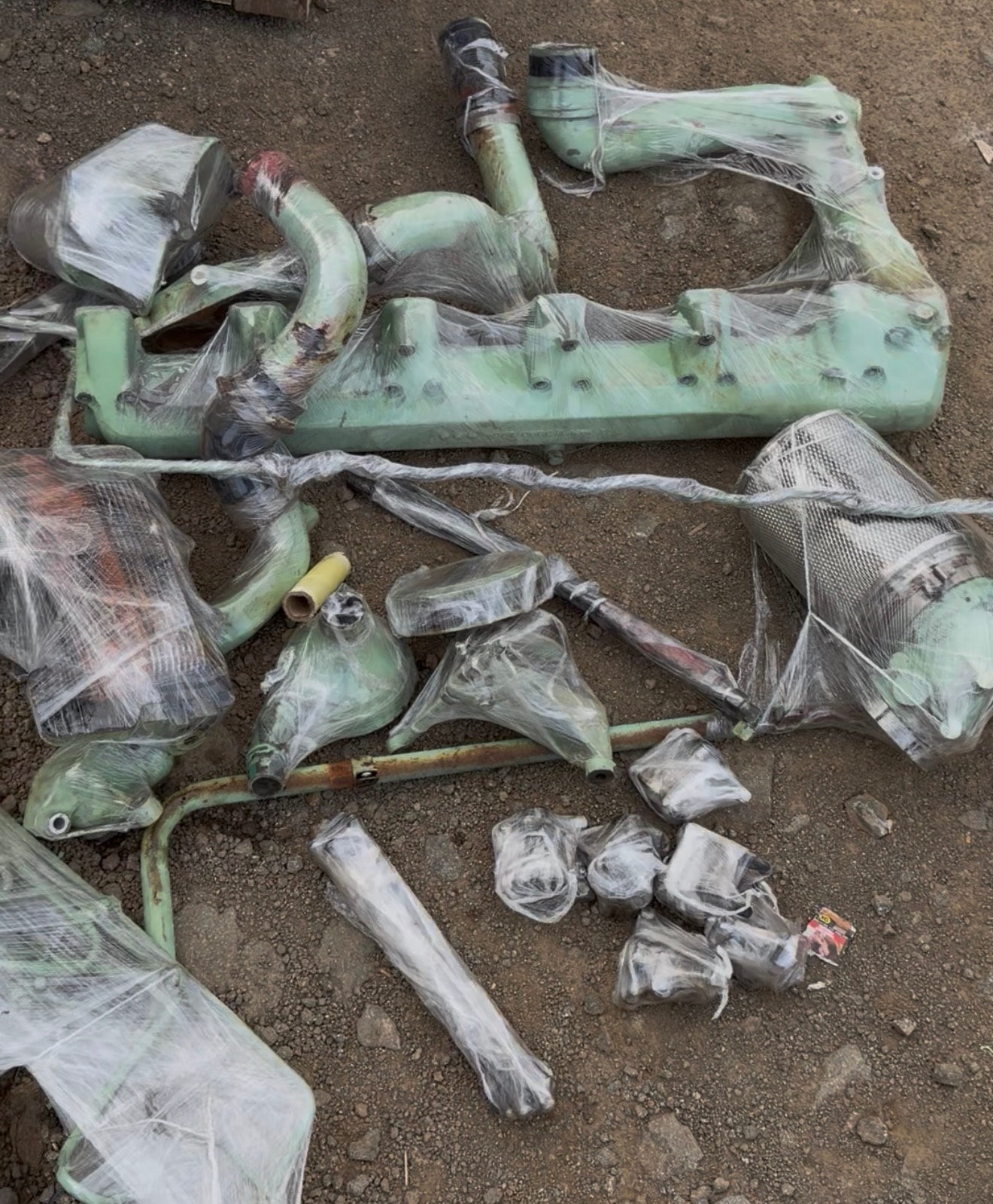 Wrapped green metal parts on ground